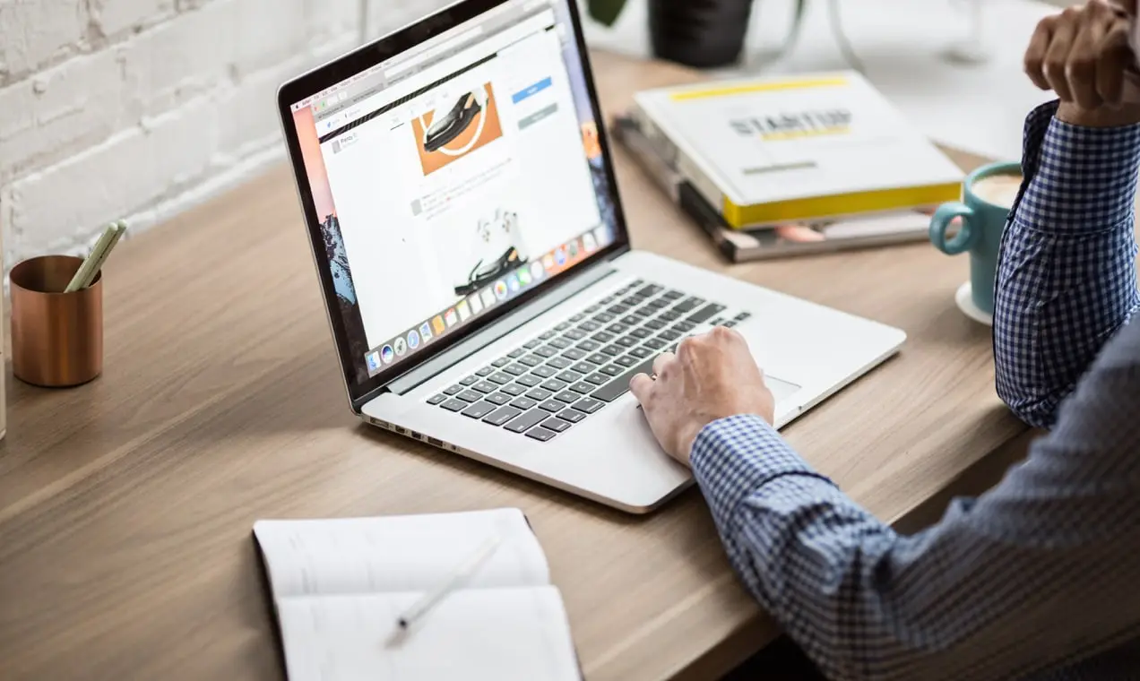 mężczyzna korzystający z laptopa przy drewnianym biurku