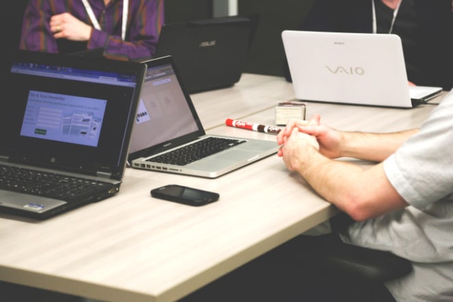 algumas pessoas com laptops sentam-se juntas em uma mesa para discutir um projeto