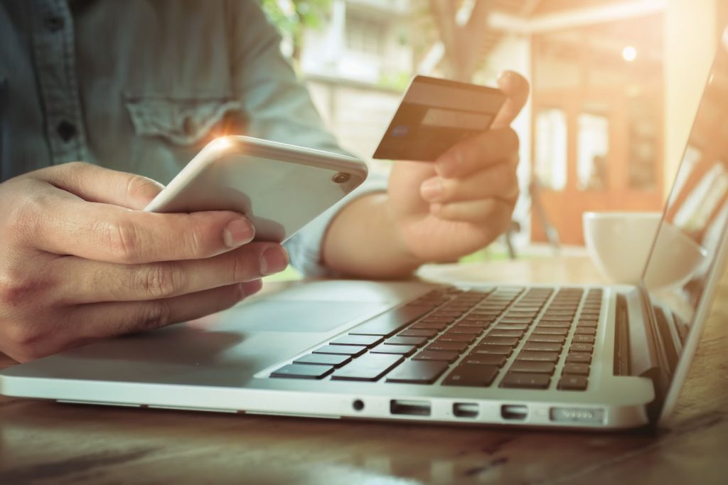 uma pessoa insere as informações do cartão de crédito pelo celular enquanto faz compras on-line