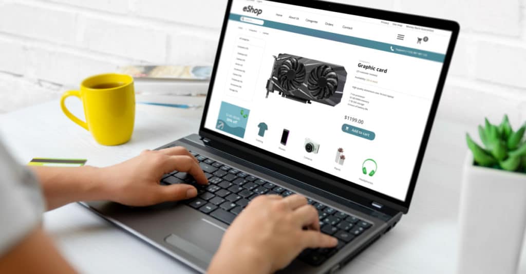 uma mulher navega em uma loja online chamada eShop em um laptop que fica ao lado de uma caneca de café amarela