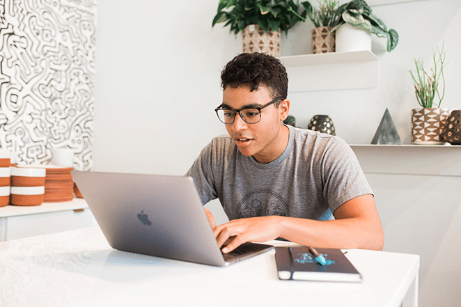 orang di ruang putih terang di laptop dan dengan notebook di dekatnya