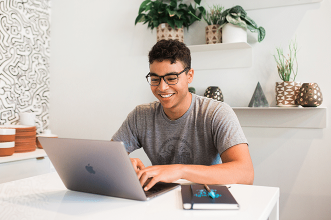 orang di ruang putih terang di laptop dan dengan notebook di dekatnya