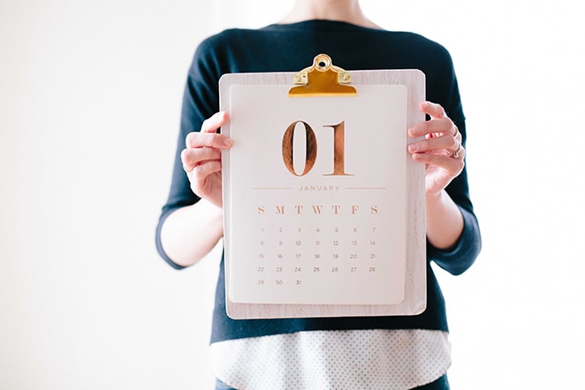mujer sosteniendo un calendario frustrado en oro en el portapapeles