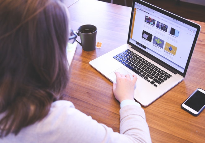 امرأة على المكتب مع موقع ويب على كمبيوتر محمول Mac