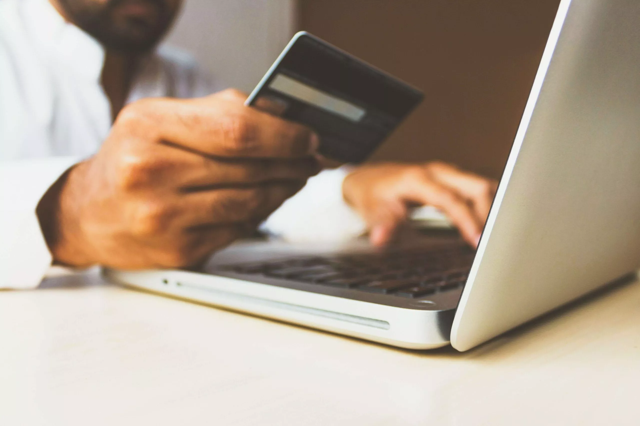 homem usando um cartão de crédito no laptop