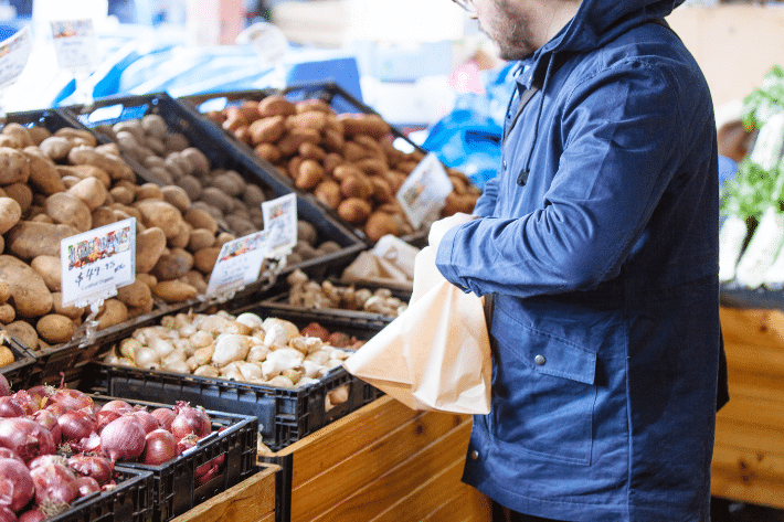 seseorang berbelanja di pasar lokal, menambahkan bawang putih ke dalam tas