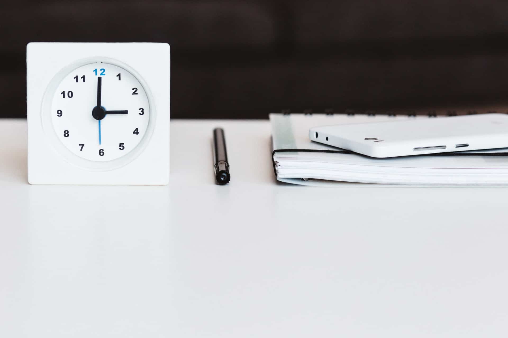 Reloj y cuaderno en el escritorio.