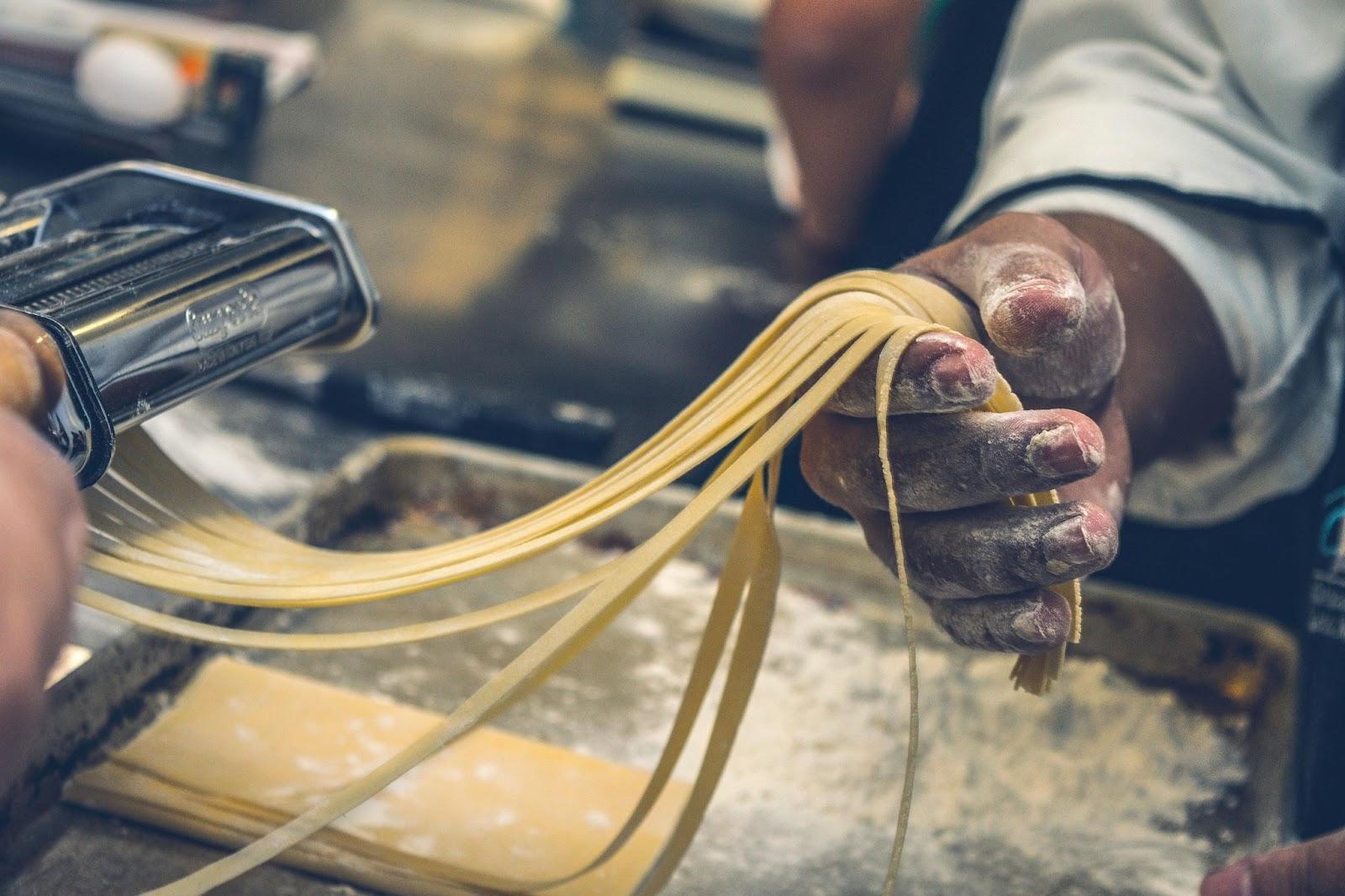 Pria membuat pasta di dapur, dengan tangan tertutup