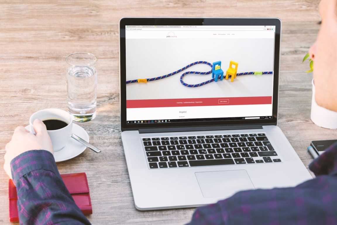 Seseorang minum kopi dan menggunakan laptop
